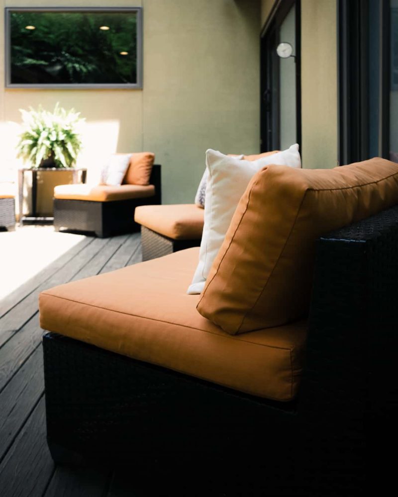 three lounge chairs on the outside porch of shoji spa with orange cushions and white pillows