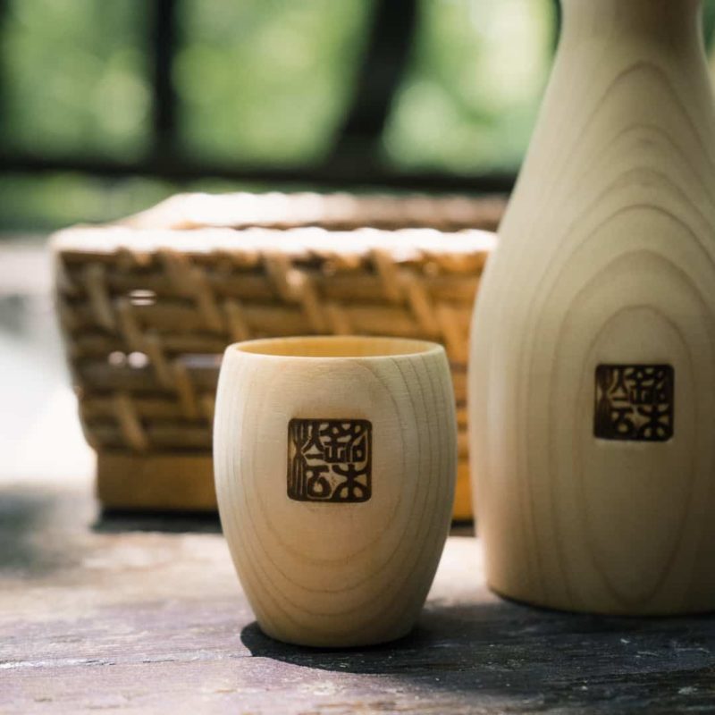 a wooden cup and bottle with japanese designs carved into the wood