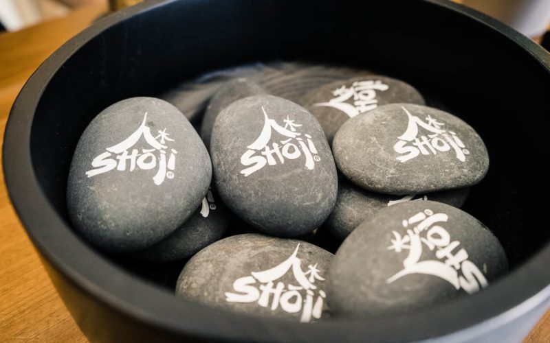 a container full of stones with the shoji logo printed on top