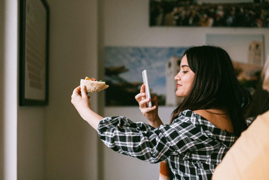 woman taking a selfie with her slice of pizza